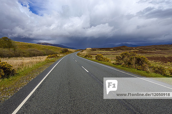 Landstraße mit dramatischen Wolken im Frühling auf der Isle of Skye in Schottland  Vereinigtes Königreich