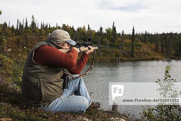 Jäger zielt mit einem Gewehr über den Iliamna-See  Südwest-Alaska  USA