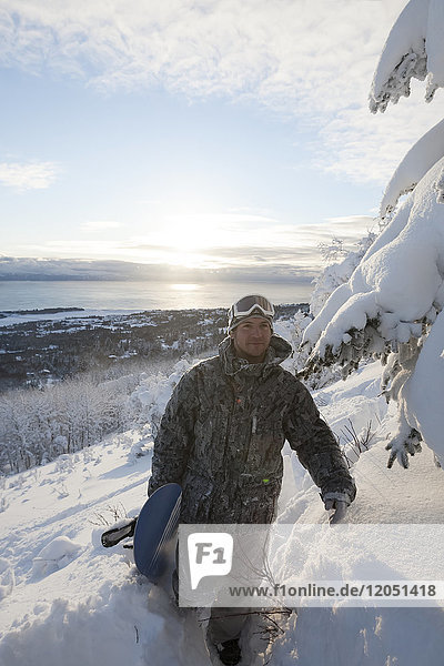 Snowboarder auf einem Hügel mit Blick auf die Kachemak Bay bei Sonnenuntergang  Homer  Southcentral Alaska  USA