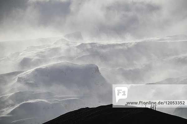 Gruppe von Fotografen Silhouette gegen den Schnee beladenen Berg; Island