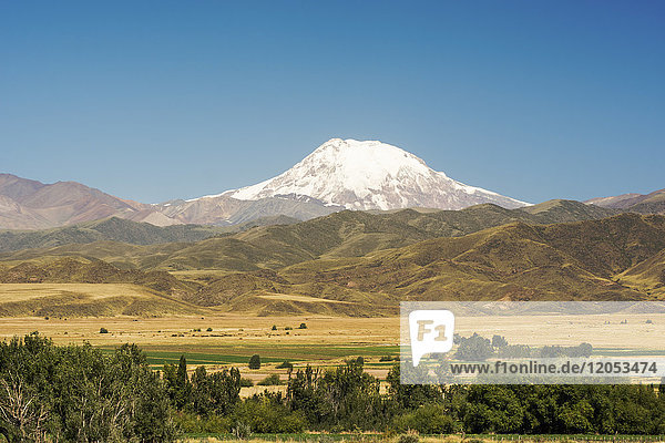 Snow-Covered Volcano Towers Over The Foothills Of The Andes And Farmlands; Mendoza  Argentina