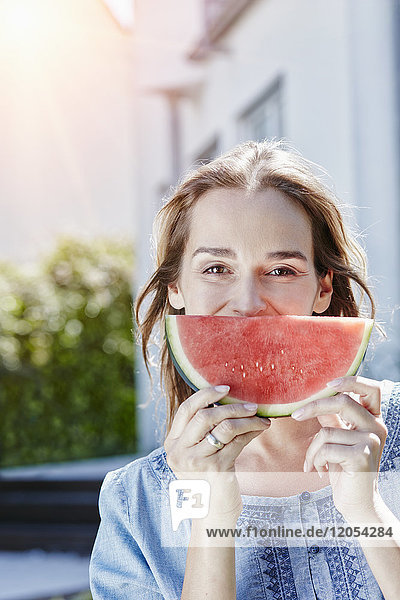 Porträt der glücklichen Frau mit Wassermelonenscheibe im Freien