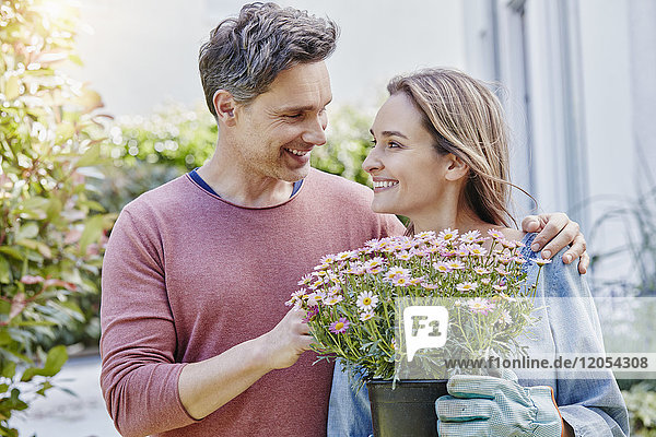 Smiling couple with flowers in front of their home