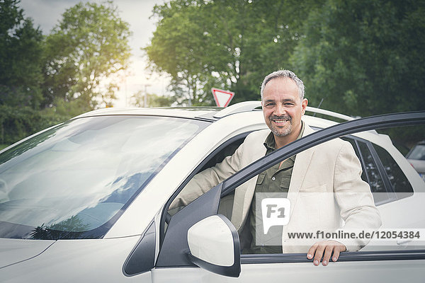 Portrait of smiling mature businessman entering his car