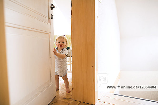 Portrait of happy baby boy opening the door