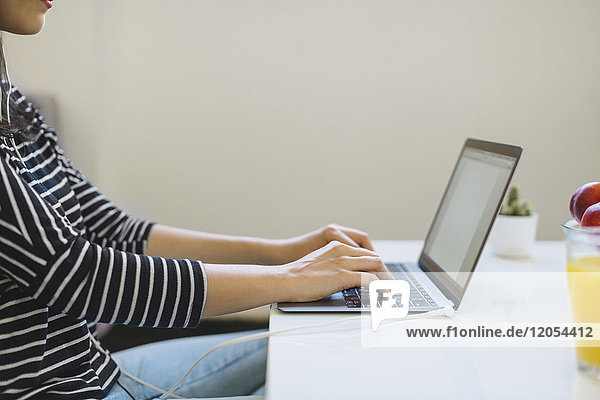 Young woman using laptop at home  partial view