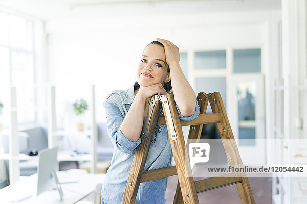 Portrait of smiling woman leaning on ladder