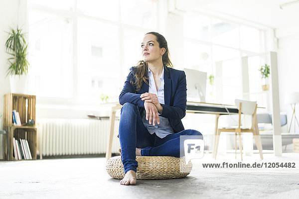 Businesswoman sitting on cushion on the floor