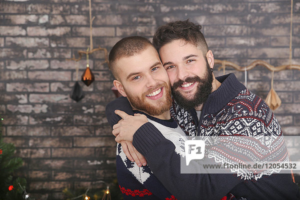 Porträt eines glücklichen schwulen Paares  das sich zu Weihnachten umarmt