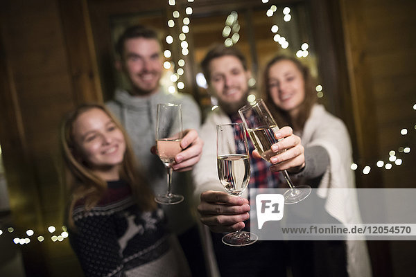Glückliche Freunde  die nachts im Freien Champagnergläser halten.