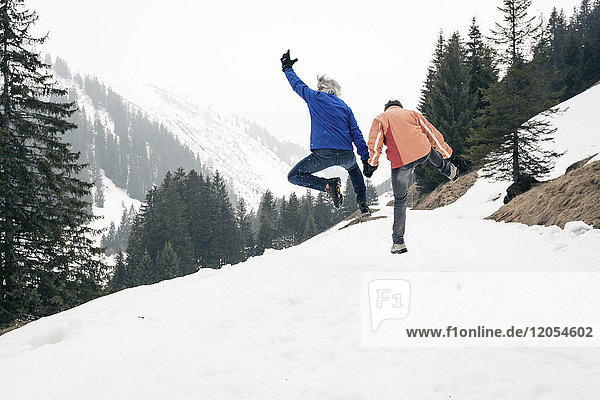 Österreich  Damuels  glückliches Seniorenpaar beim Springen in der Winterlandschaft