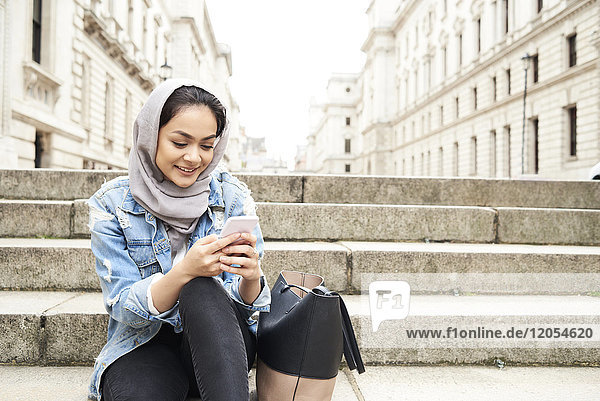 UK  England  London  junge Frau in Hijab mit Handy in der Stadt
