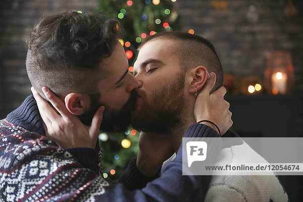 Schwules Paar zur Weihnachtszeit zu Hause küssen
