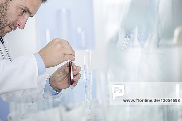 Mann untersucht Reagenzglas mit Flüssigkeit im Labor