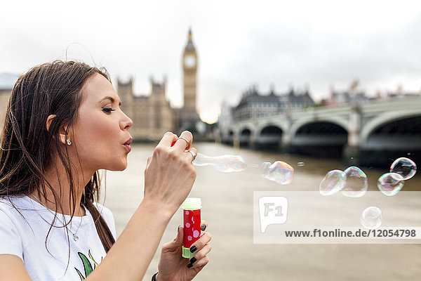 UK  London  woman making soap bubbles near Westminster Bridge