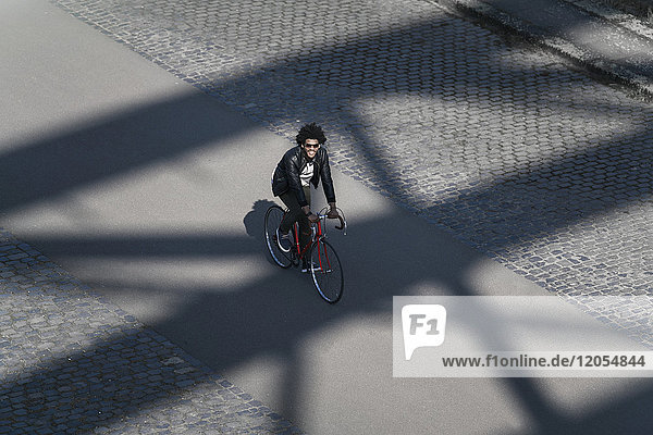 Erhöhter Blick auf den lächelnden Mann mit Sonnenbrille auf dem Fahrrad