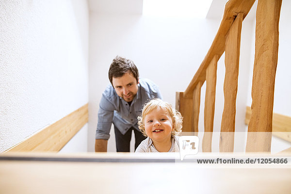 Father with little boy on wooden stairs at home