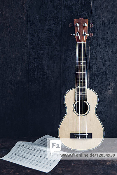 Ukulele mit Akkordkarte vor dunklem Hintergrund