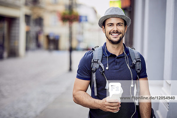 Portrait eines Reisenden mit Rucksack  der Kaffee hält