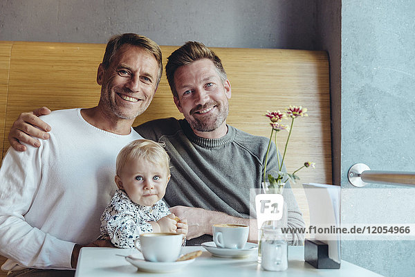 Porträt eines glücklichen schwulen Paares mit ihrem Baby im Cafe