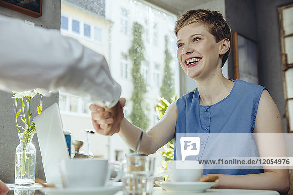 Geschäftsmann und Geschäftsfrau beim Händeschütteln im Cafe