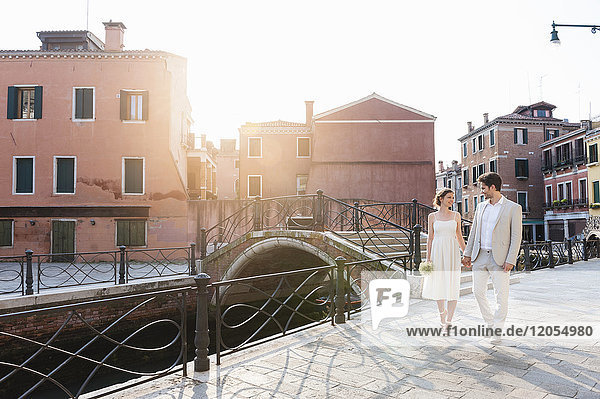 Italien  Venedig  Brautpaar geht bei Sonnenaufgang Hand in Hand