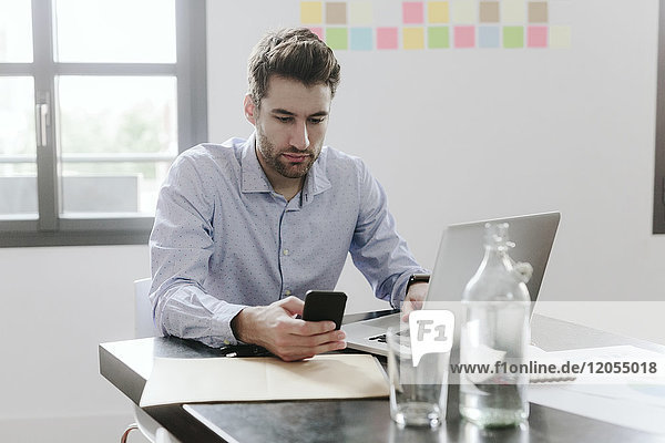 Young businessman working in office  using smartphone and laptop