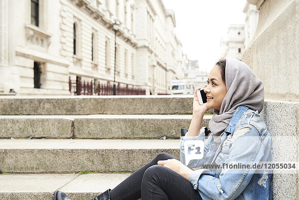 UK  England  London  junge Frau mit Hijab am Handy in der Stadt