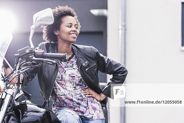 Smiling young woman with her motorcycle