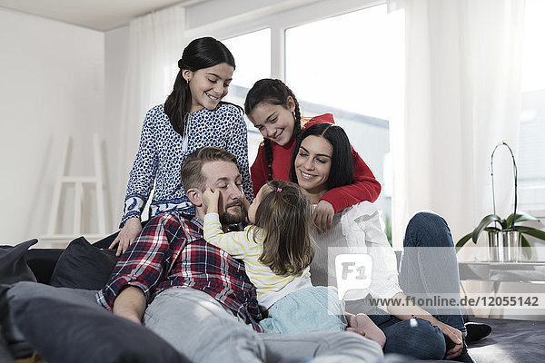 Eltern und drei Töchter auf Sofa im Wohnzimmer