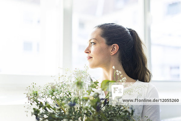 Frau mit Blumen aus dem Fenster schauend