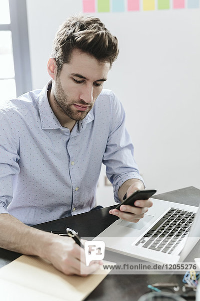 Young businessman working in office  using smartphone and laptop