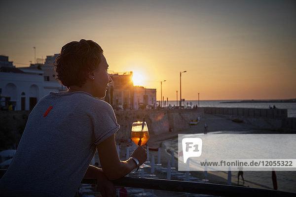 Italy  Santa Maria al Bagno  woman relaxing with glass of Spritz at sunset