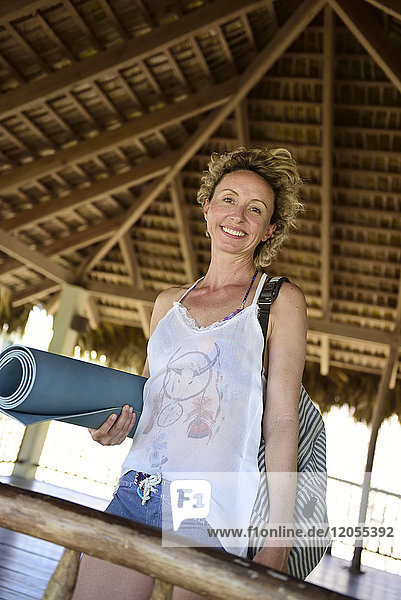 Portrait of smiling woman holding yoga mat