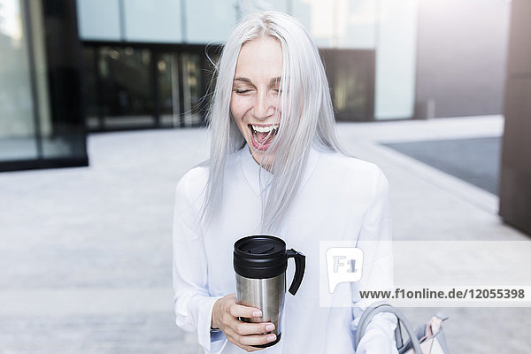 Schreiende junge Geschäftsfrau mit Kaffeetasse in der Stadt