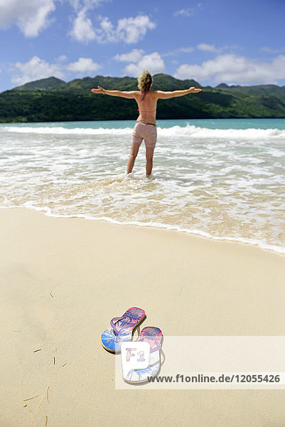 Dominikanische Republik  Samana  Flip-Flops am Strand und Frau im Meer