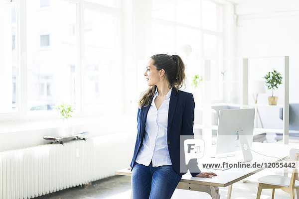 Businesswoman leaning on desk looking out of window