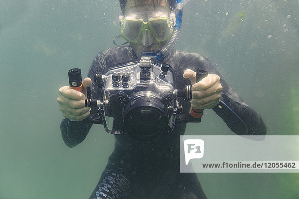 Mann taucht mit Unterwasser-DSLR-Kameragehäuse