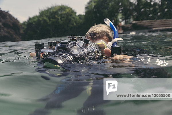 Mann mit Unterwasser-DSLR-Kameragehäuse im See
