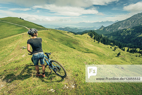 Germany  Bavaria  Pfronten  woman with mountain bike on alpine meadow near Aggenstein