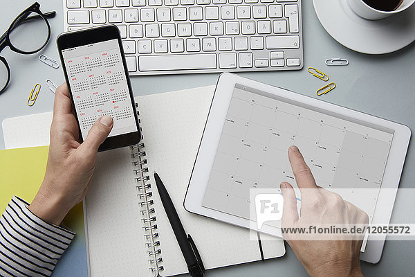 Draufsicht der Frau mit Smartphone und Tablett mit Kalender auf dem Schreibtisch