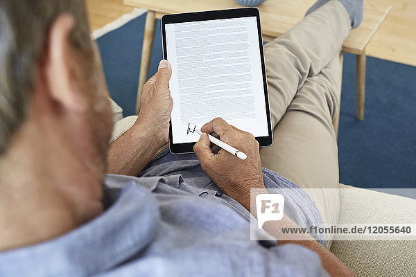 Mature man signing digital contract on tablet
