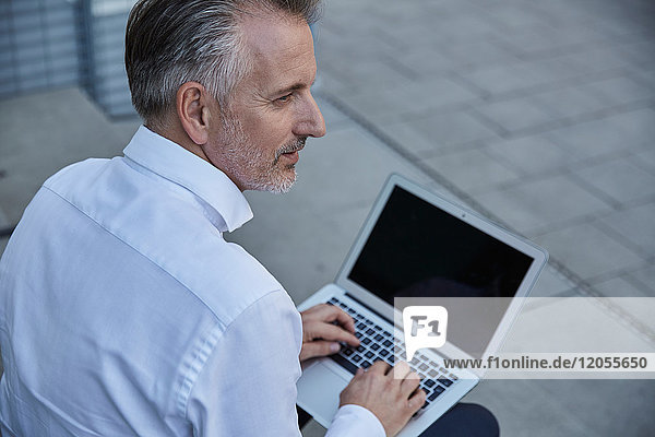 Portrait eines Geschäftsmannes mit Laptop im Freien
