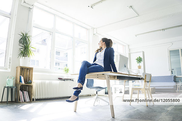 Businesswoman sitting on table in a loft