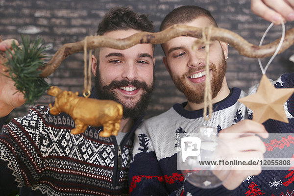 Schwules Paar schmückt einen Zweig zur Weihnachtszeit