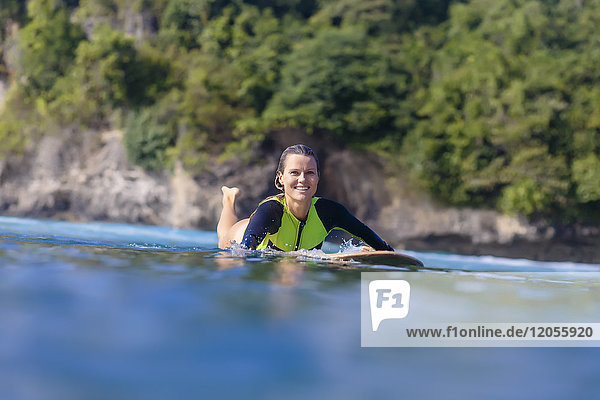 Indonesien  Bali  lächelnde Frau auf dem Surfbrett liegend