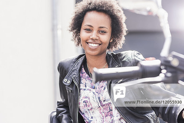 Porträt einer lächelnden jungen Frau mit ihrem Motorrad