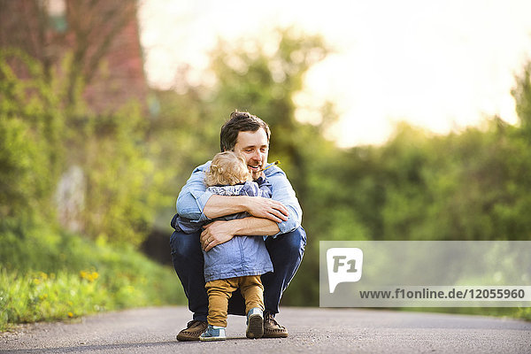 Father hugging little boy on field path