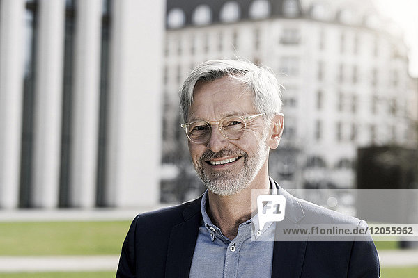 Grey-haired businessman smiling into camera