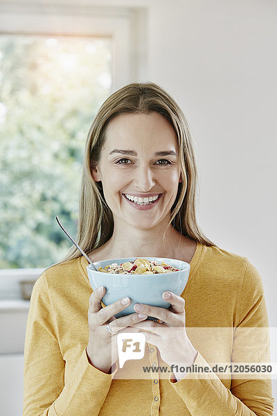 Portrait of happy woman holding bowl with muesli